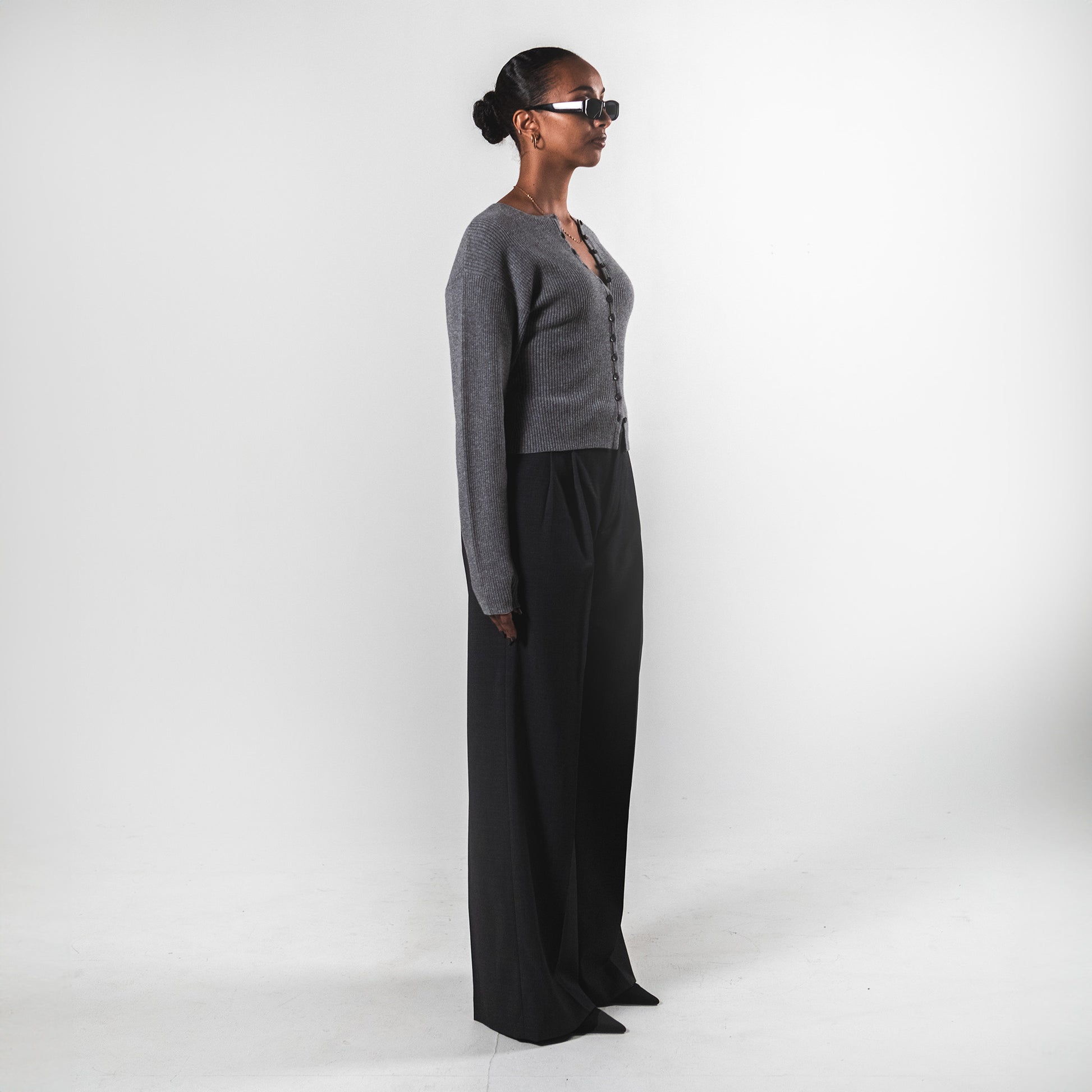 Side fron view of a model wearing a grey rib knit cardigan by SÎAMO SOCIÉTÉ