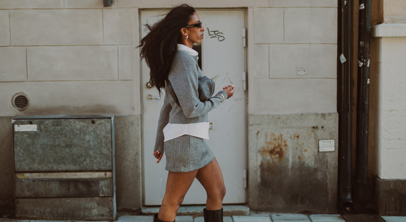 Woman walking on a sidewalk next to a building with graffiti.