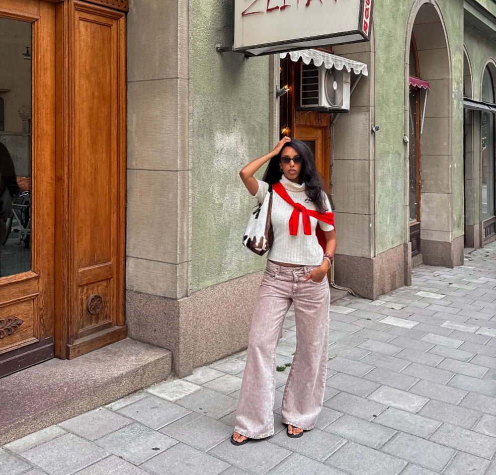 Woman standing on a street in front of a building with a sign.